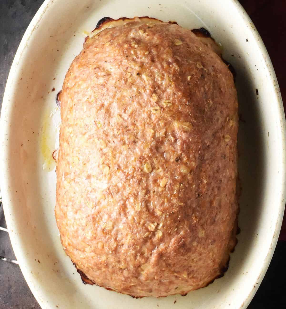 Baked oaty meatloaf in oval white ceramic dish.