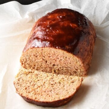 Side view of cut meatloaf with oats and glaze on parchment paper.