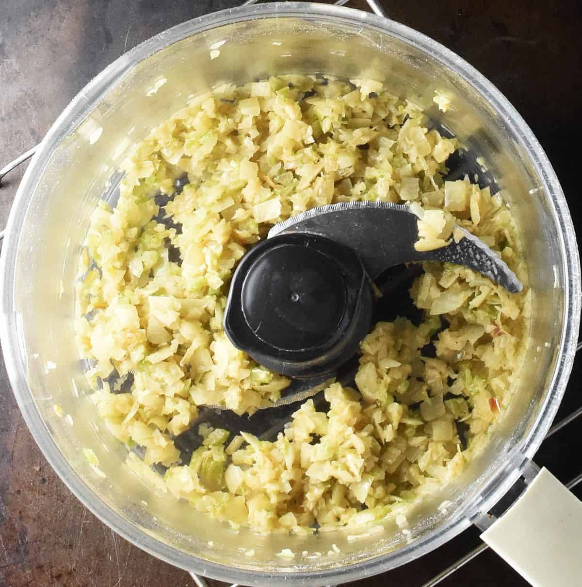 Top down view of pulsed onion mixture in food processor bowl.
