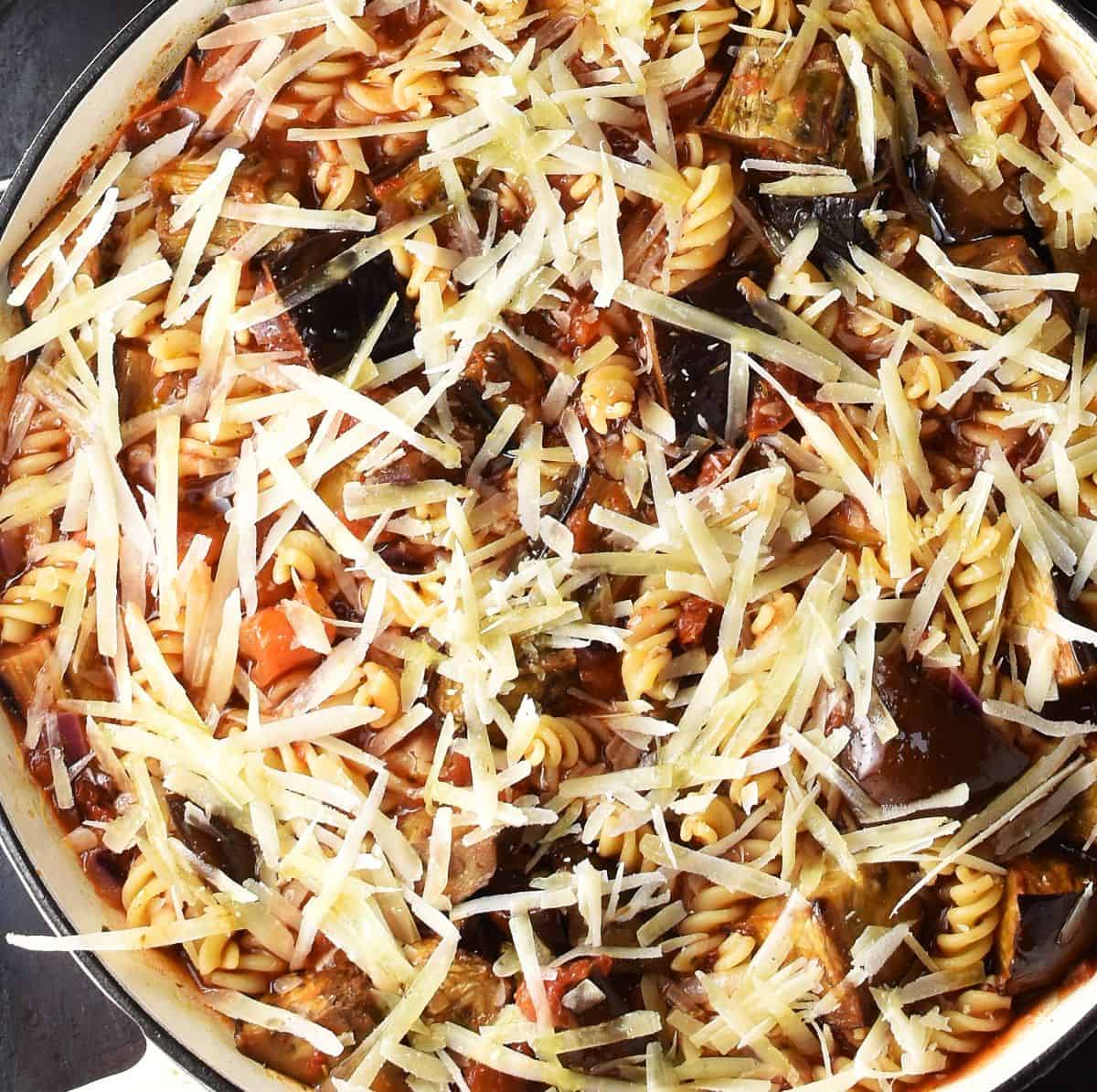 Top down view of assembled eggplant with pasta and cheese on top in large shallow pan.