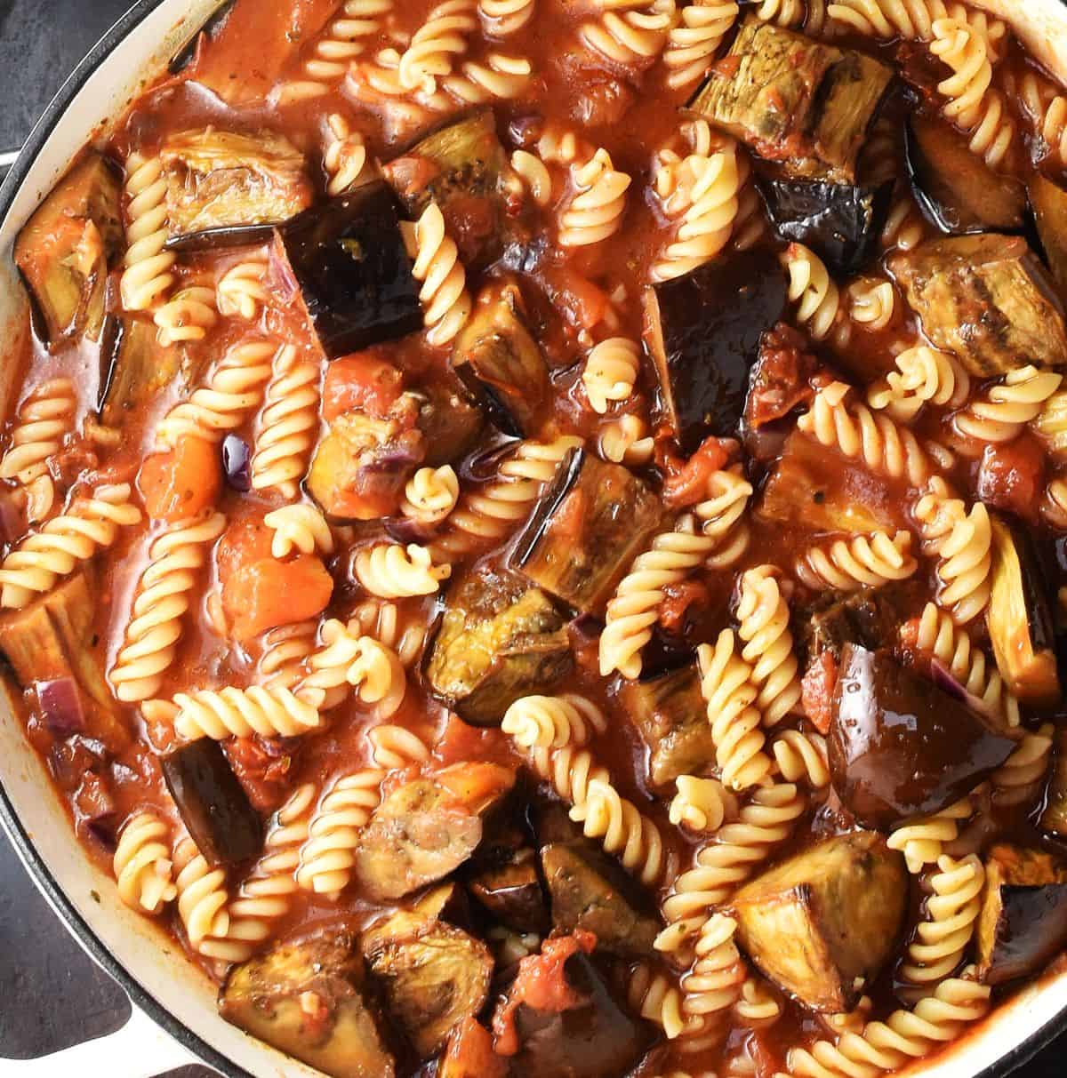 Assembled pasta and eggplant with tomato sauce in large shallow pan.