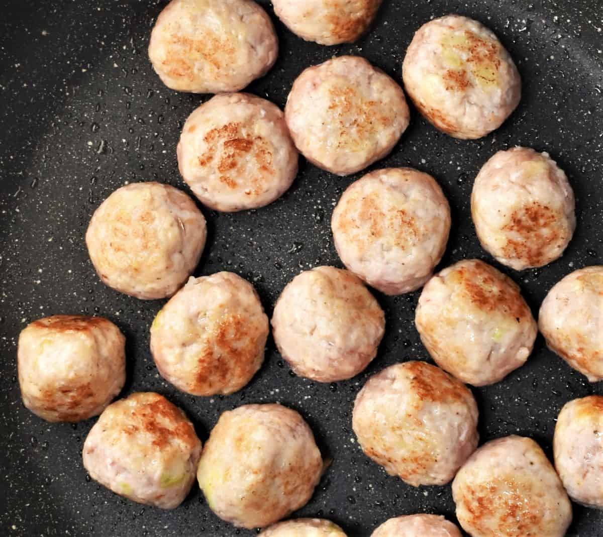 Browning chicken meatballs in pan.