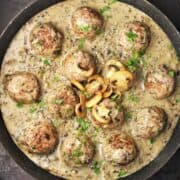 Top down view of meatballs in mushroom sauce in large pan.