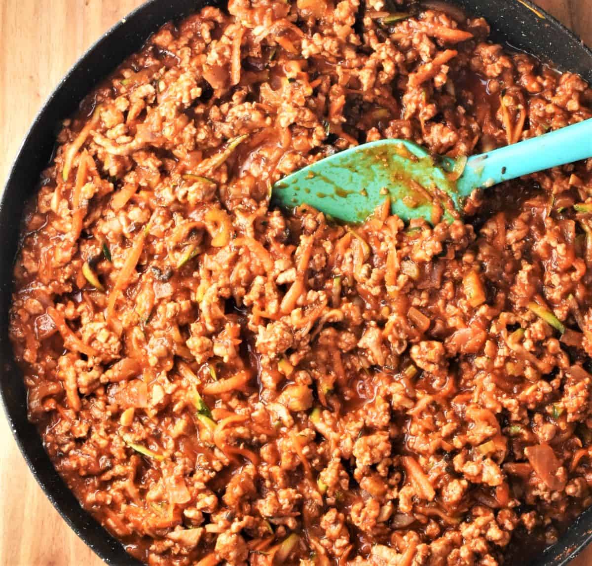 Lasagna with turkey filling mixture in large shallow pan with spoon.