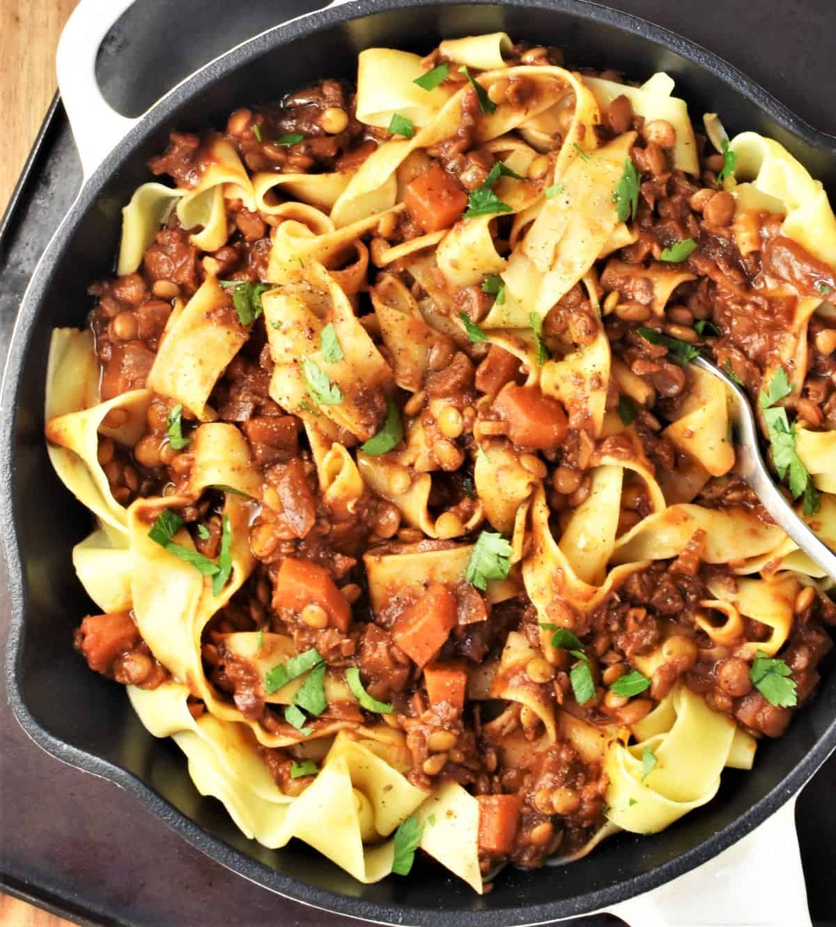 Top down view of ragu with lentils and pasta in skillet.