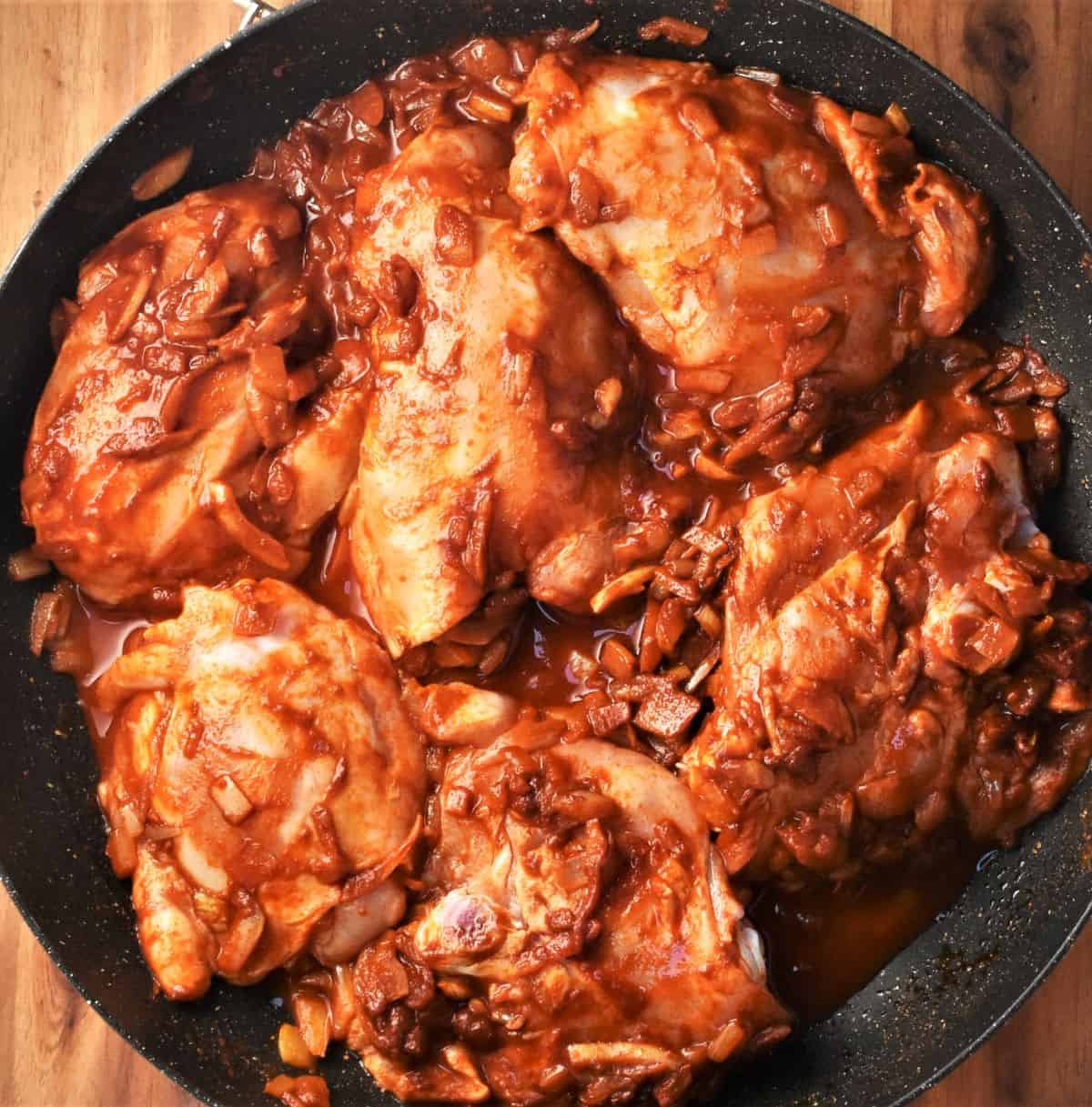 Chicken thighs in paprika sauce with pureed tomato and chopped onion.