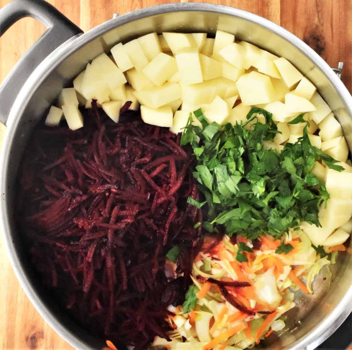Shredded beets, diced potatoes and parsley in large pot.