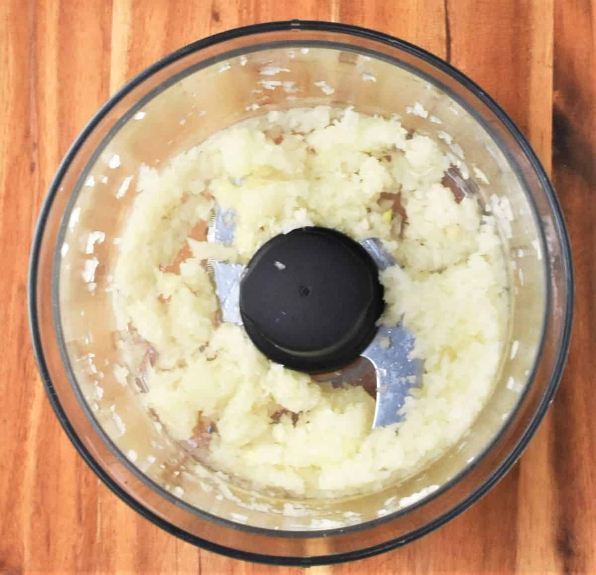 Top down view of blended onion mixture in food processor bowl.