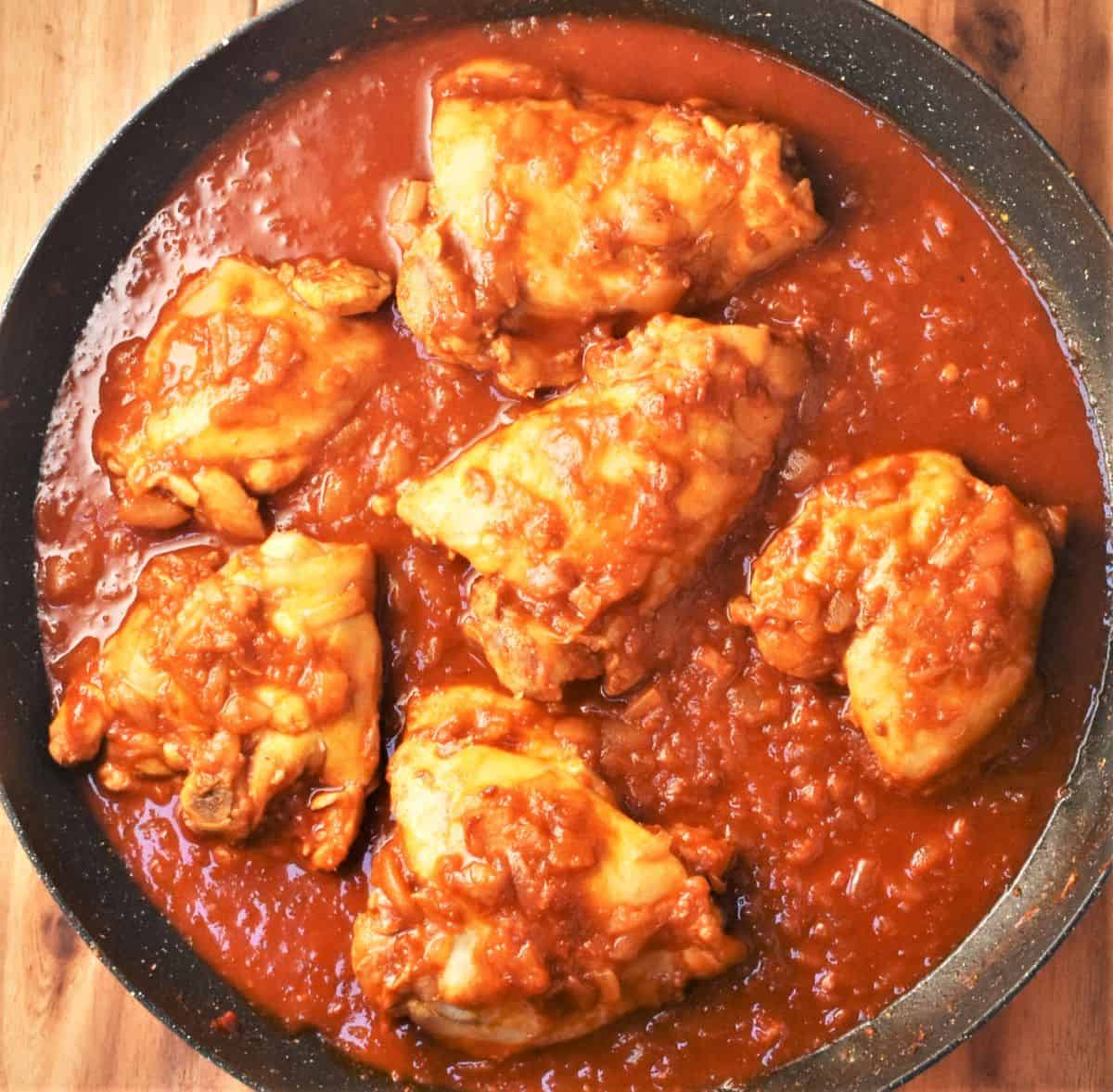 6 chicken thighs in creamy paprika sauce in shallow pan.