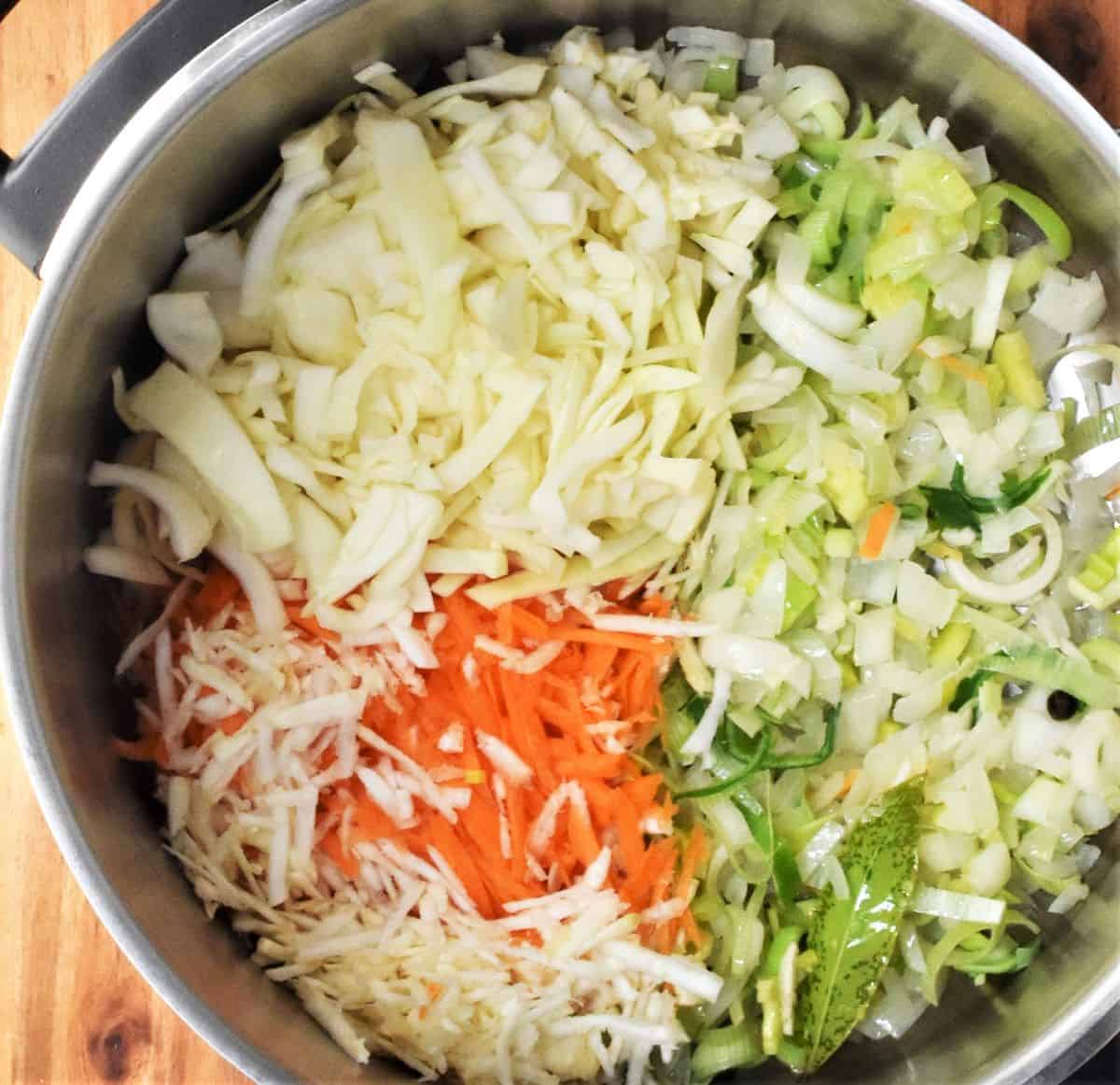 Making soup base with shredded vegetables in large pot.