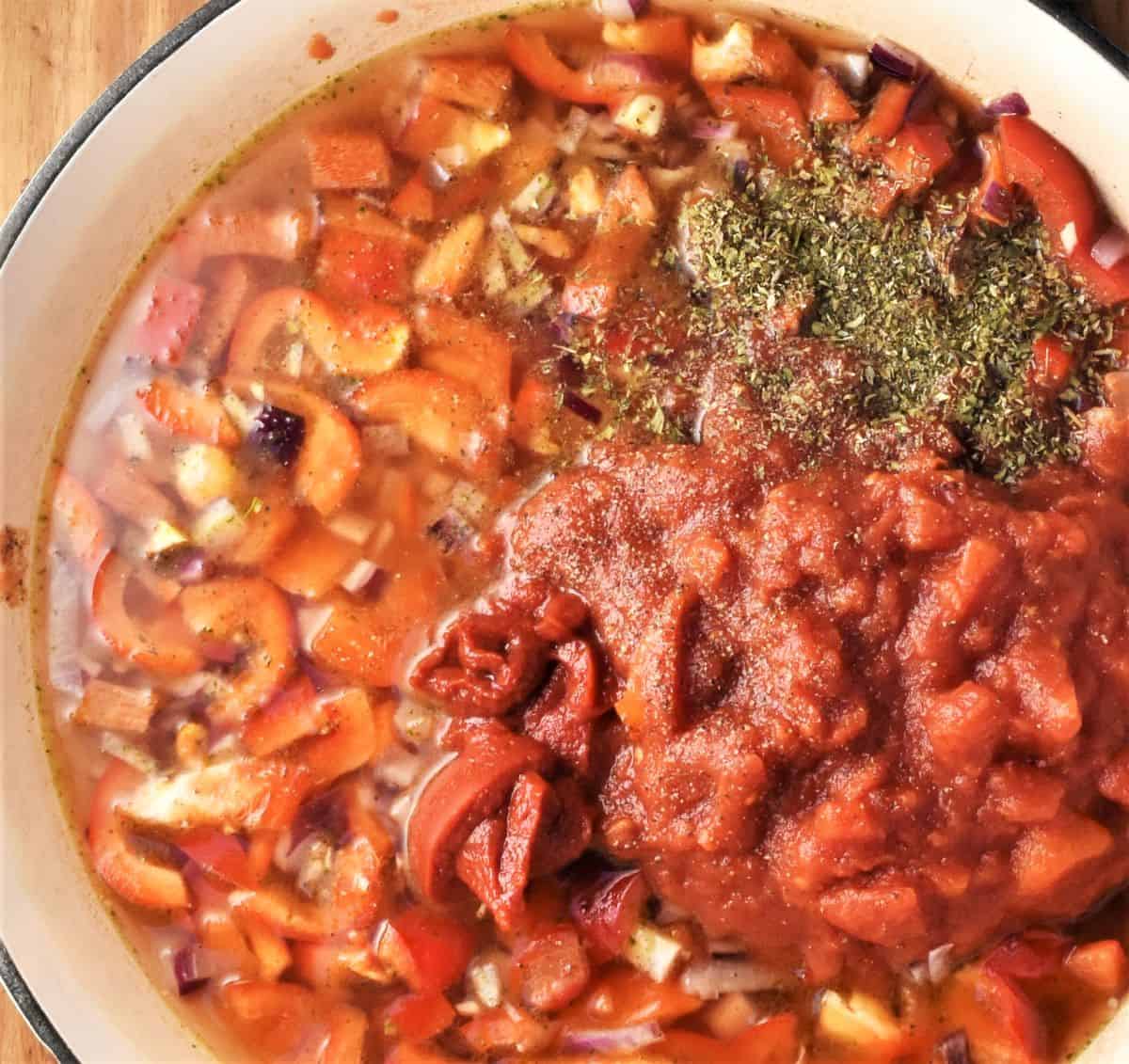 Making tomato sauce for baked pasta with meatballs in shallow large pan.