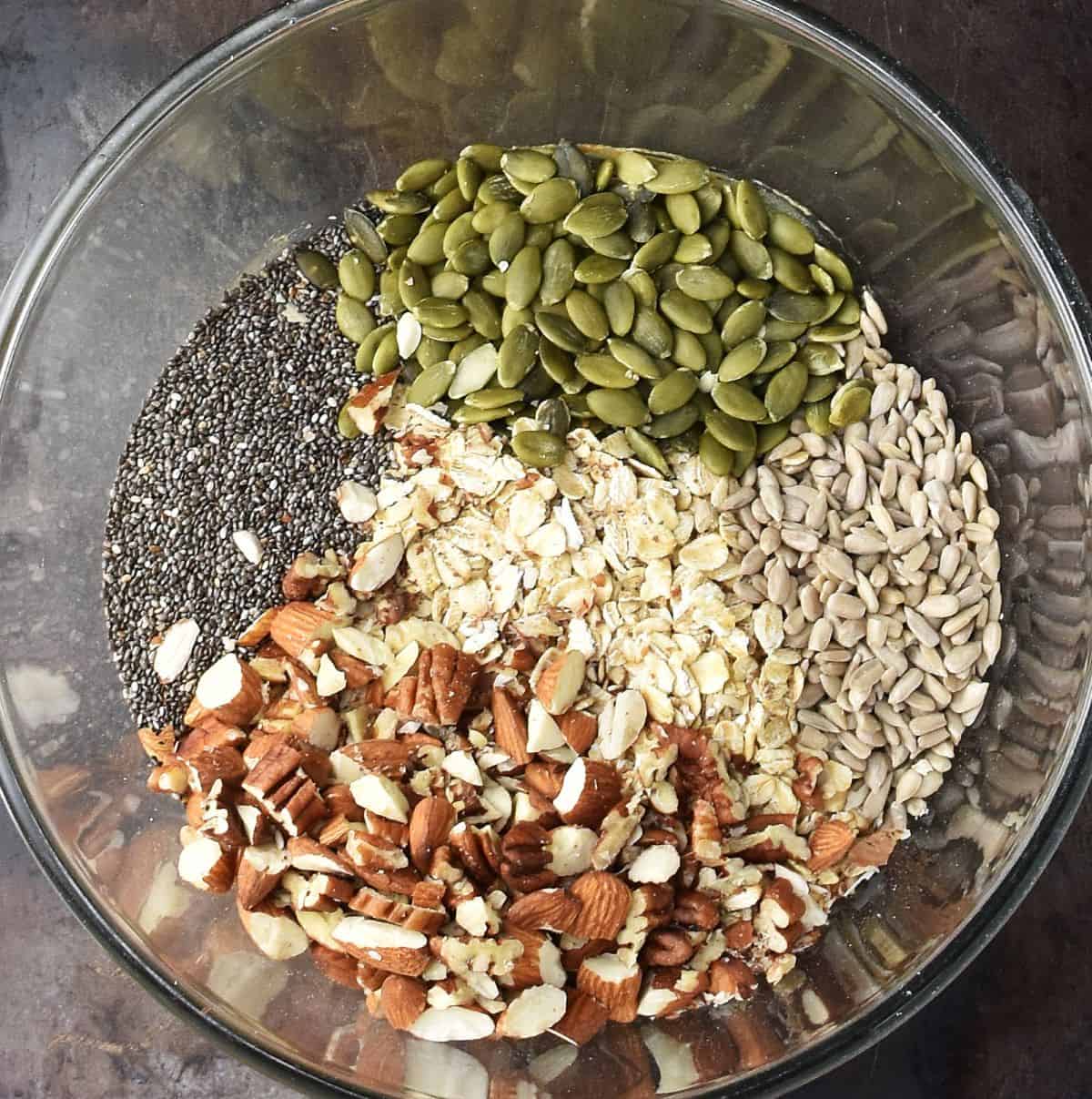 Top down view of dry ingredients for making homemade granola bars in glass bowl.