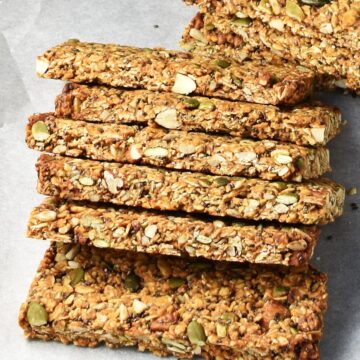 Side view of homemade protein granola bars overlapping one another on parchment.