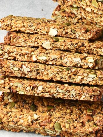 Side view of homemade protein granola bars overlapping one another on parchment.