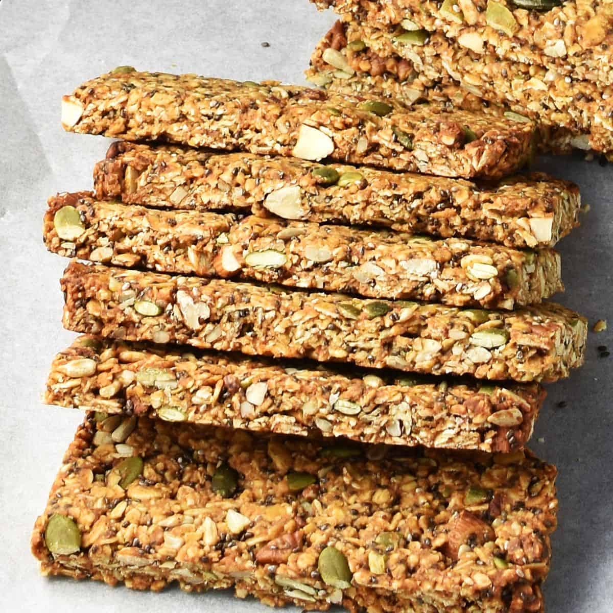 Side view of homemade protein granola bars overlapping one another on parchment.