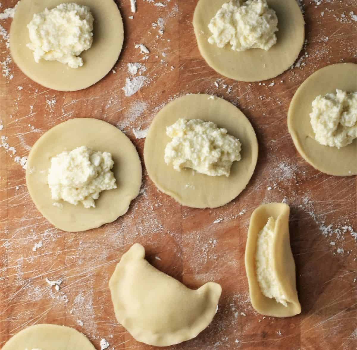 Placing filling mixture on top of dough rounds and forming pierogi.