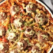 Top down view of meatball pasta bake with melted cheese in large shallow dish.
