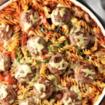 Top down view of meatball pasta bake with melted cheese in large shallow dish.