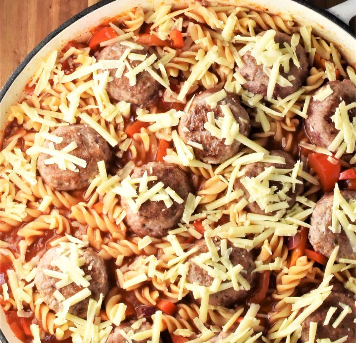 Meatball and pasta casserole with grated cheese on top in large shallow dish.
