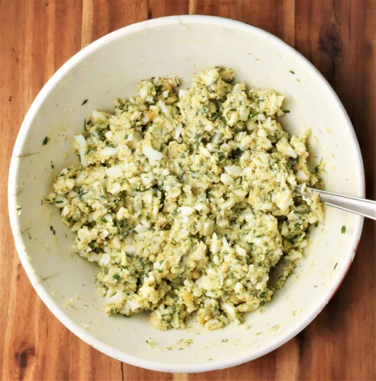 Egg patties batter in mixing bowl with spoon.