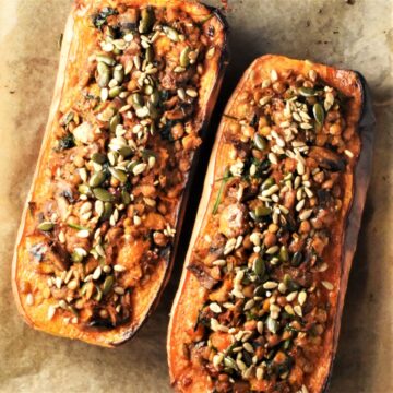 Top down view of 2 stuffed butternut squash halves on parchment.