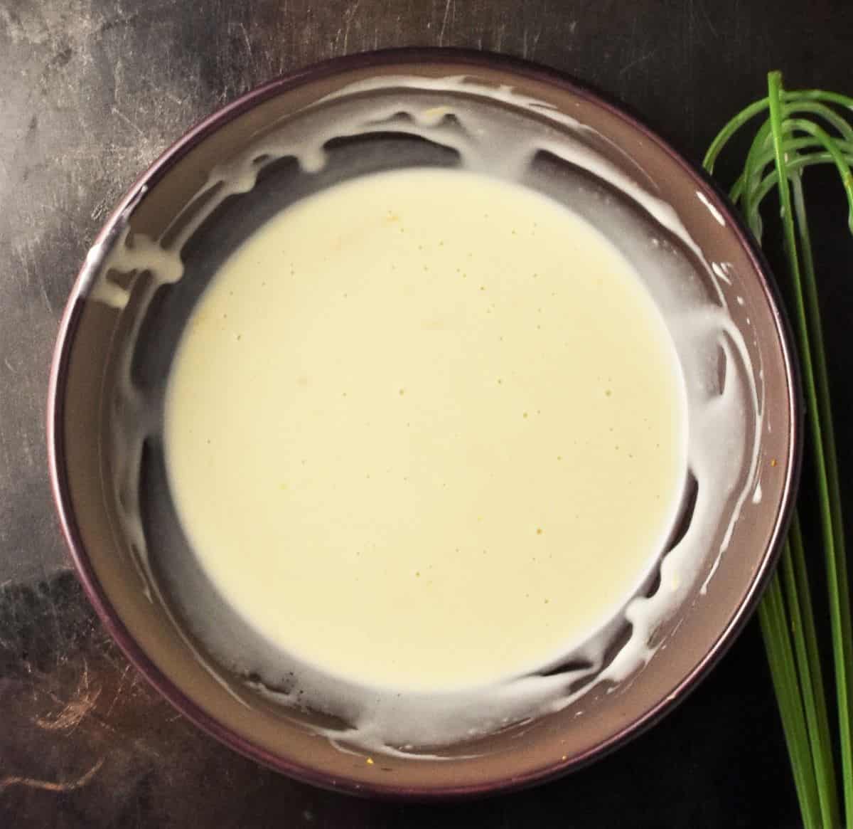 Top down view of creamy salad dressing in purple bowl.