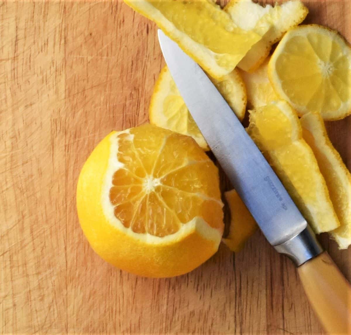 Peeling orange with rind and knife on cutting board.