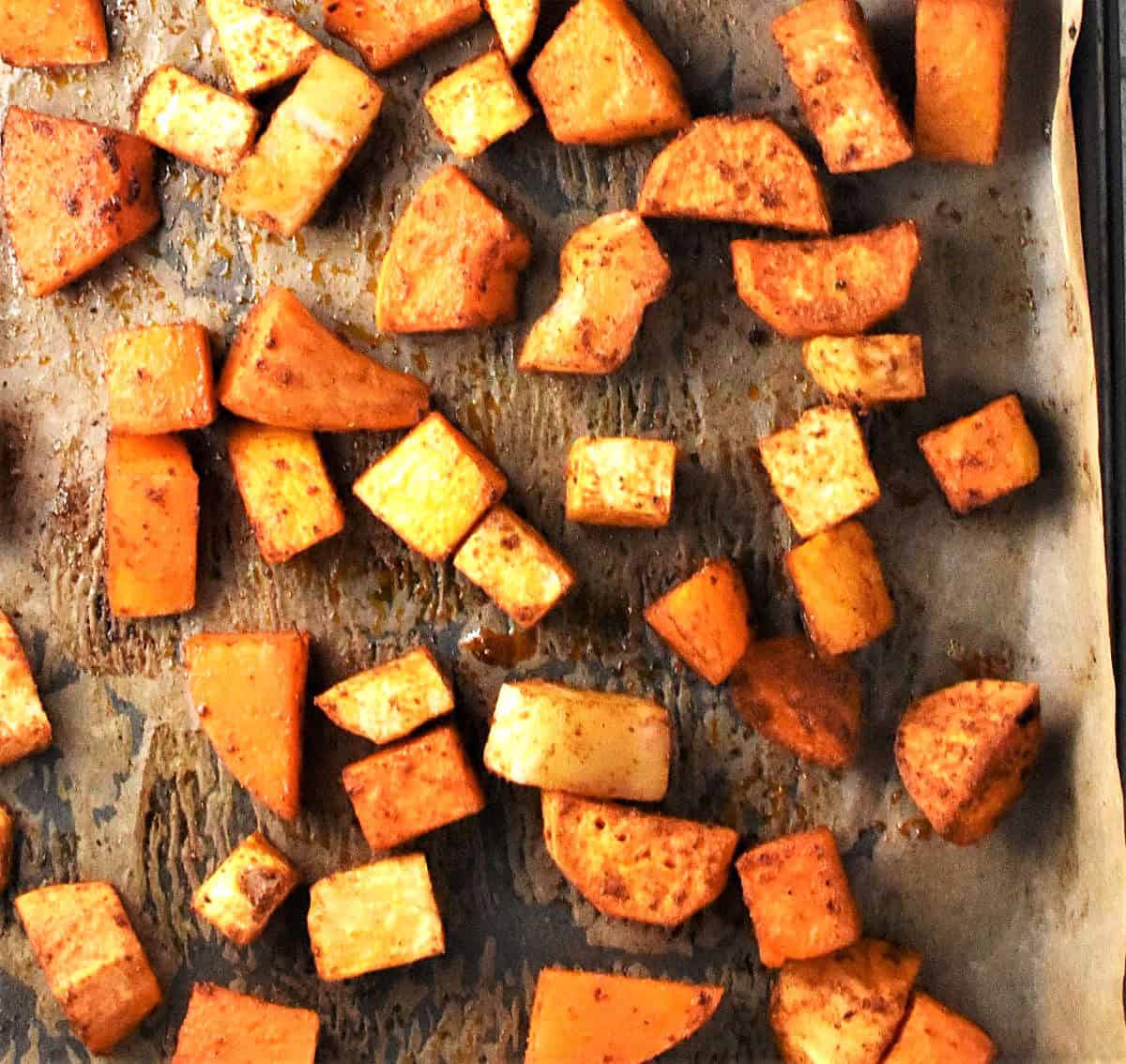 Top down view of roasted chunks for vegetables on parchment.