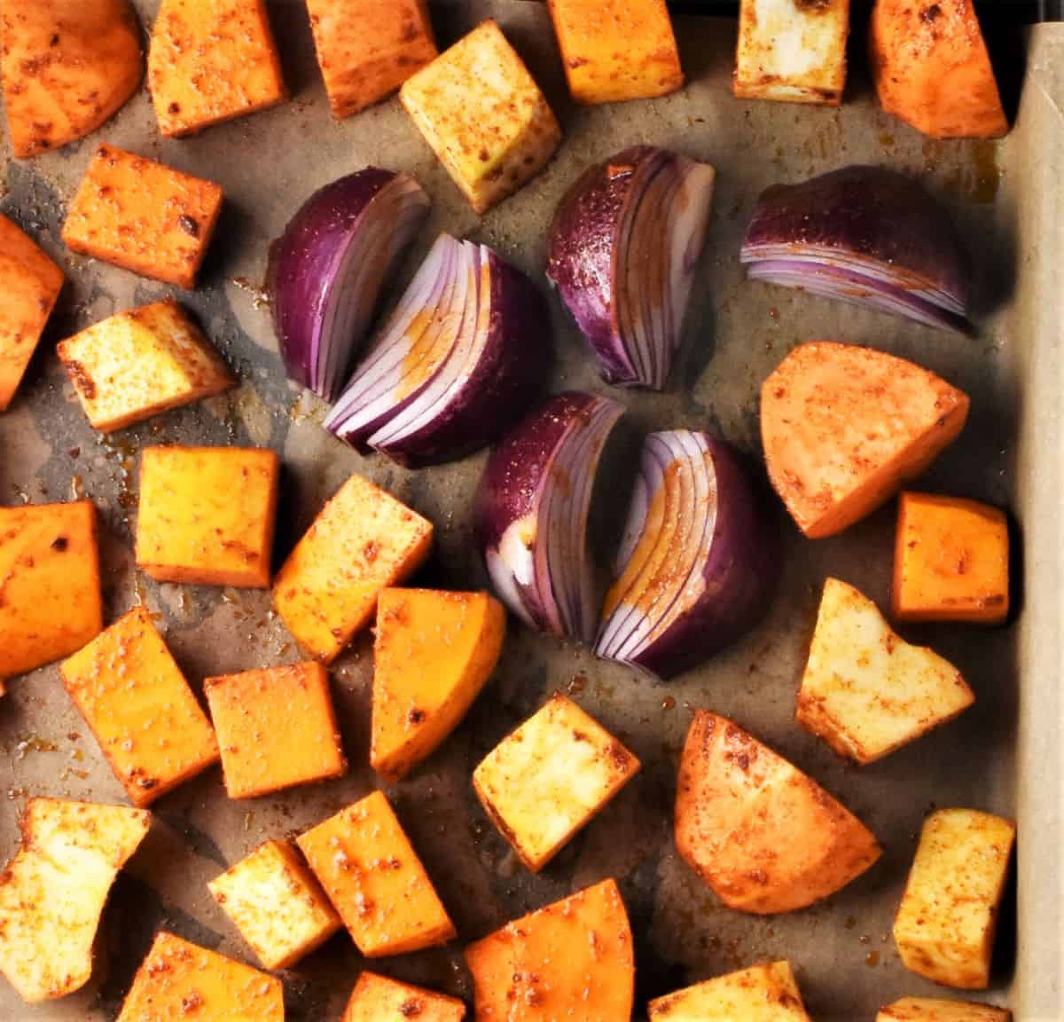 Spiced cubed vegetables on baking sheet.