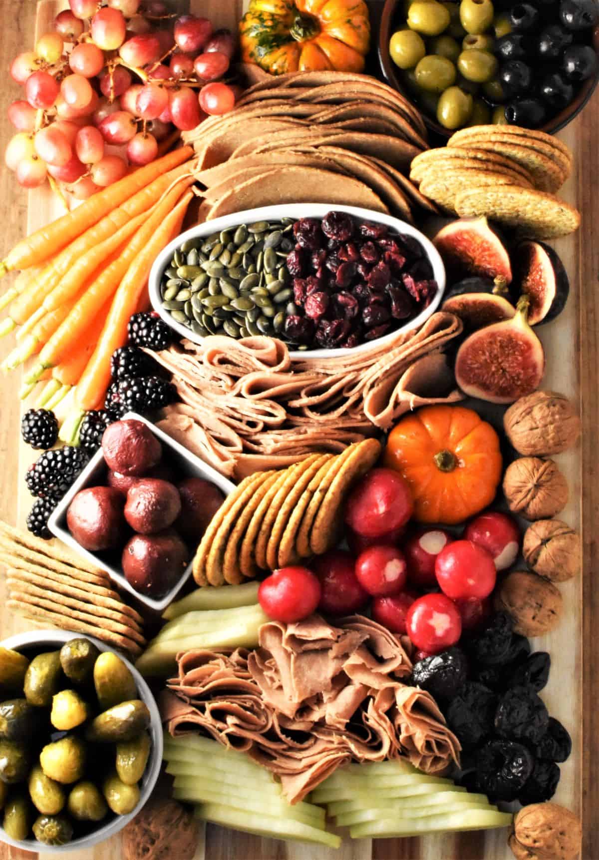 Top down view of vegan platter with meats, fruit, veg, crackers and nuts.