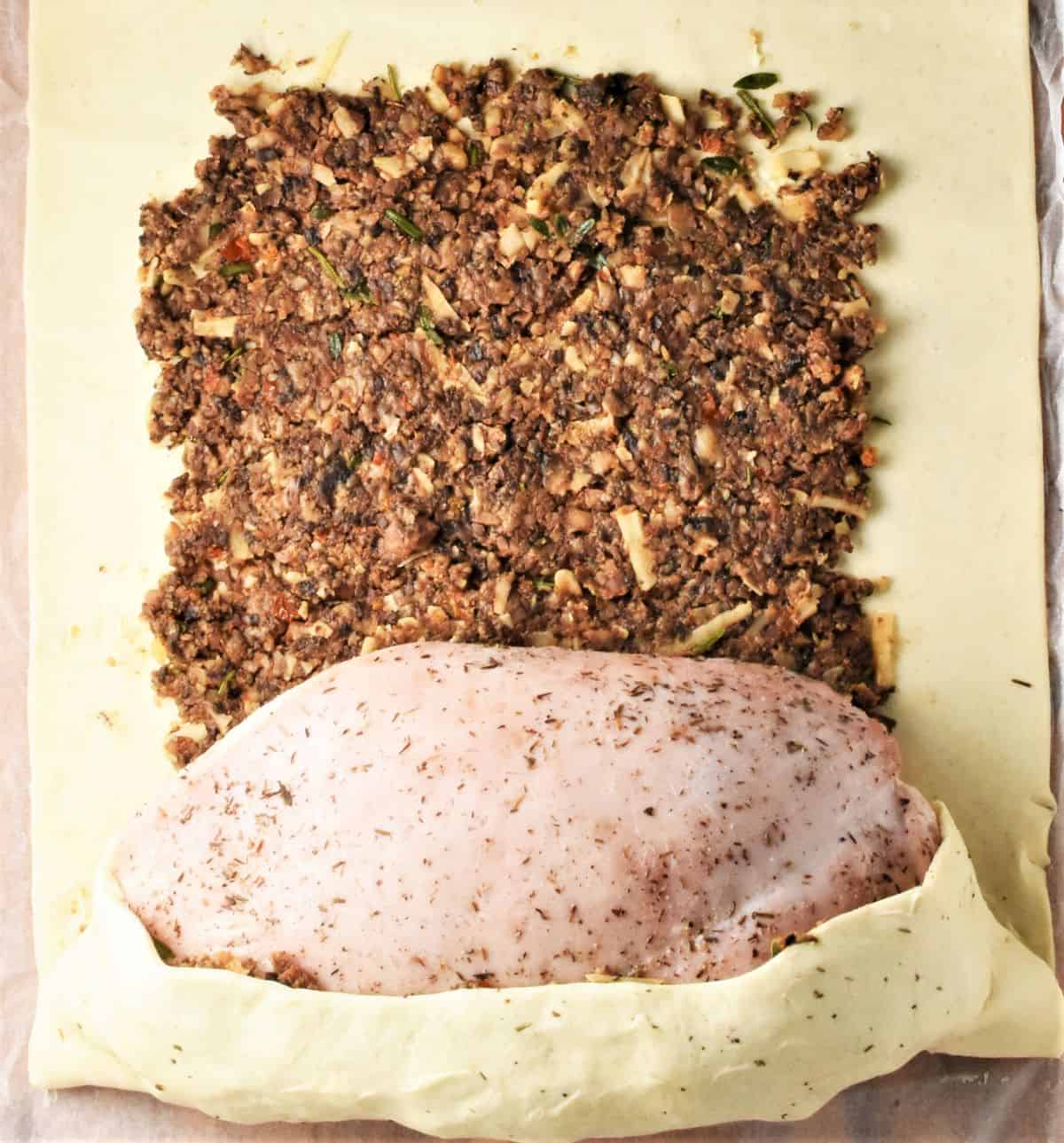 Wrapping turkey breast in mushroom filling and pastry.