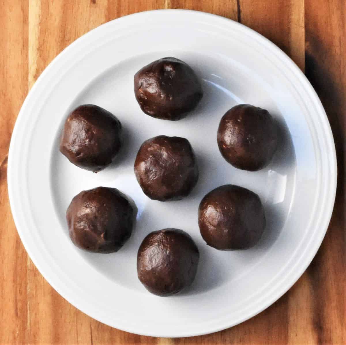 7 chocolate balls on top of white plate.