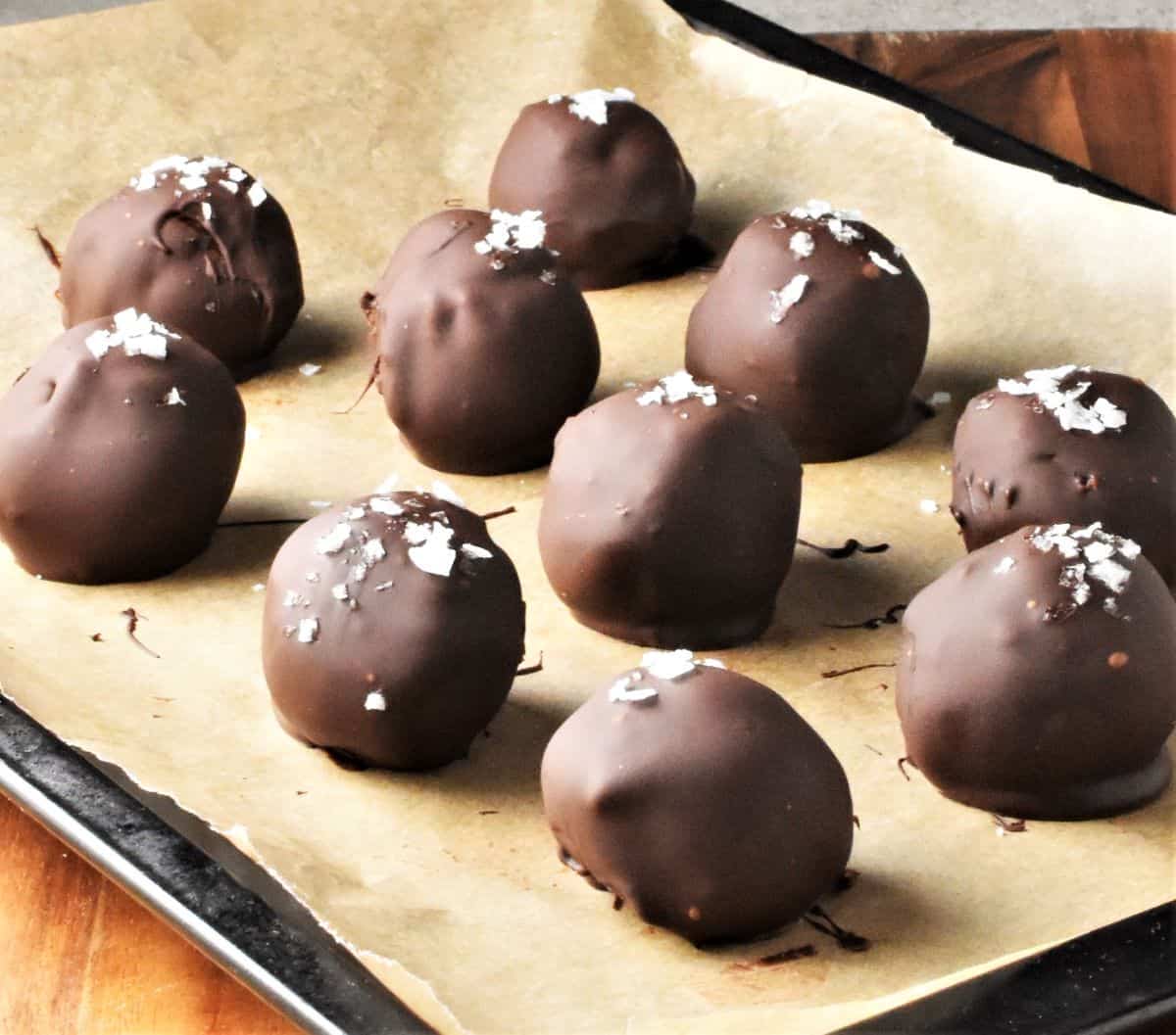 Side view of chocolate covered truffles on top of parchment.