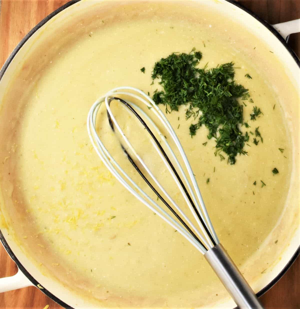 Creamy white sauce with dill for turkey breast cutlets with whisk in shallow pan.