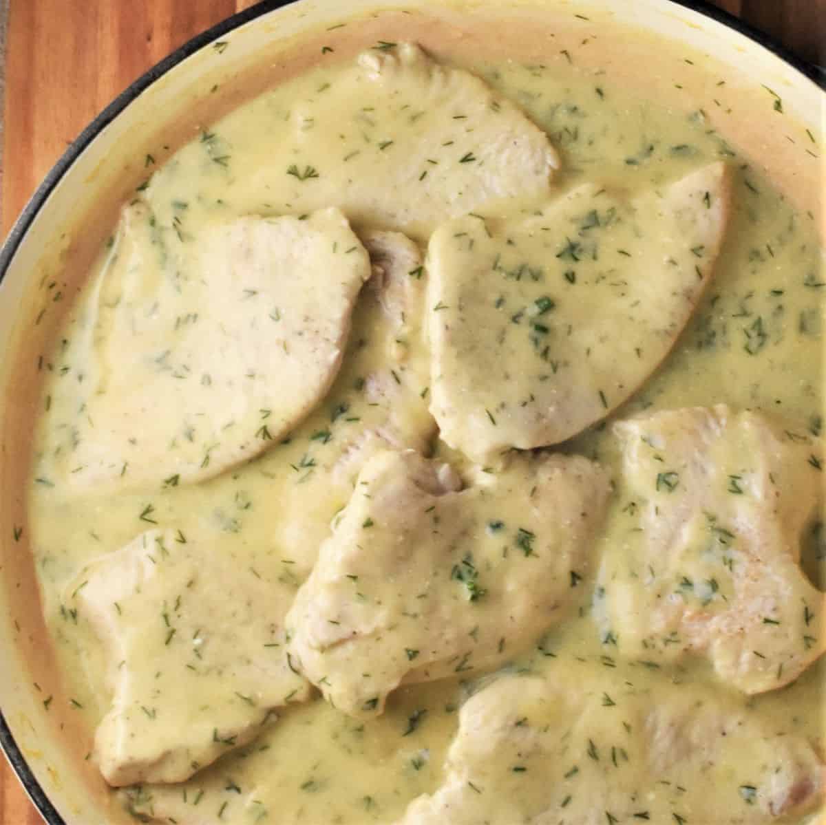 Turkey breast cutlets in creamy sauce in large pan.