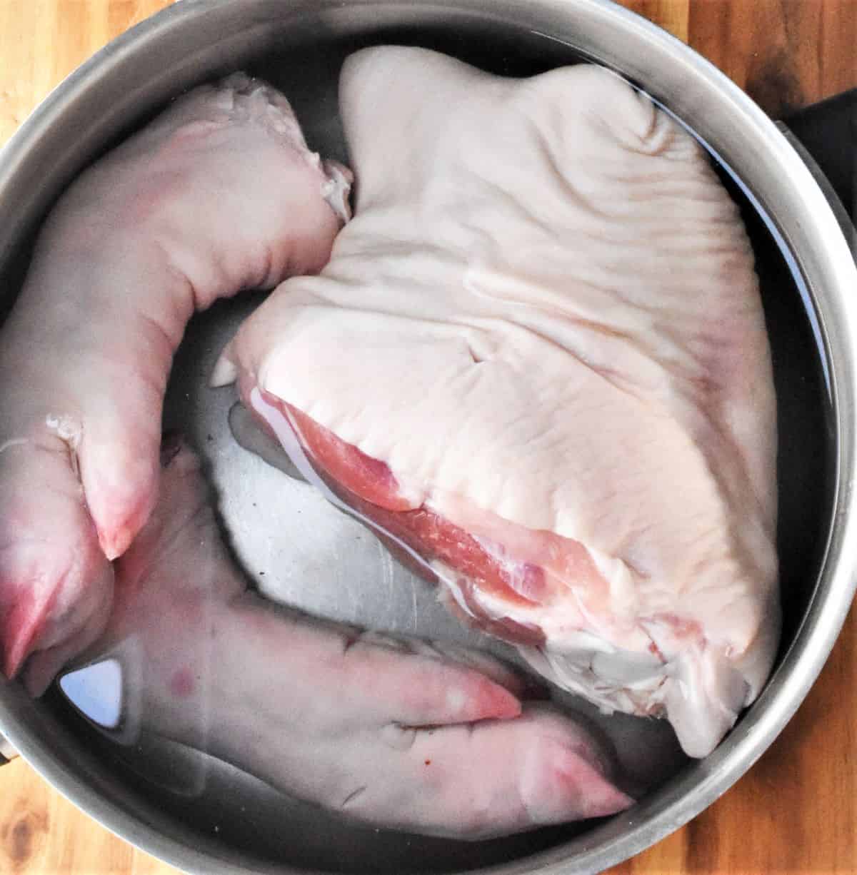 Pork shank and 2 trotters in pot with water.