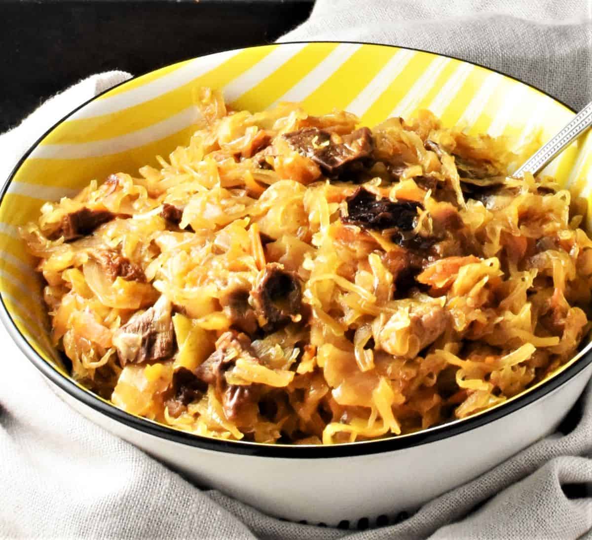 Side view of mushroom sauerkraut in yellow bowl.