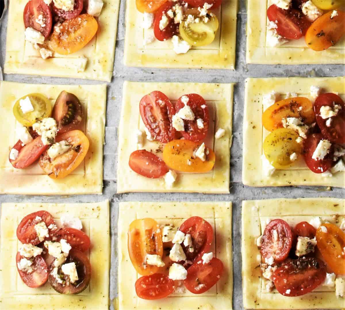 Top down view of puff pastry squares with mini tomatoes and feta on top.
