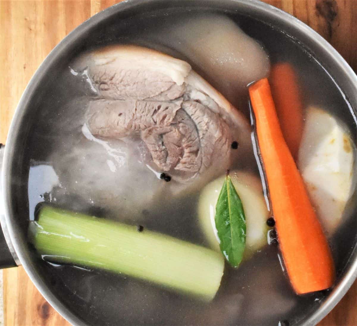 Meat and vegetables in large pot with water.