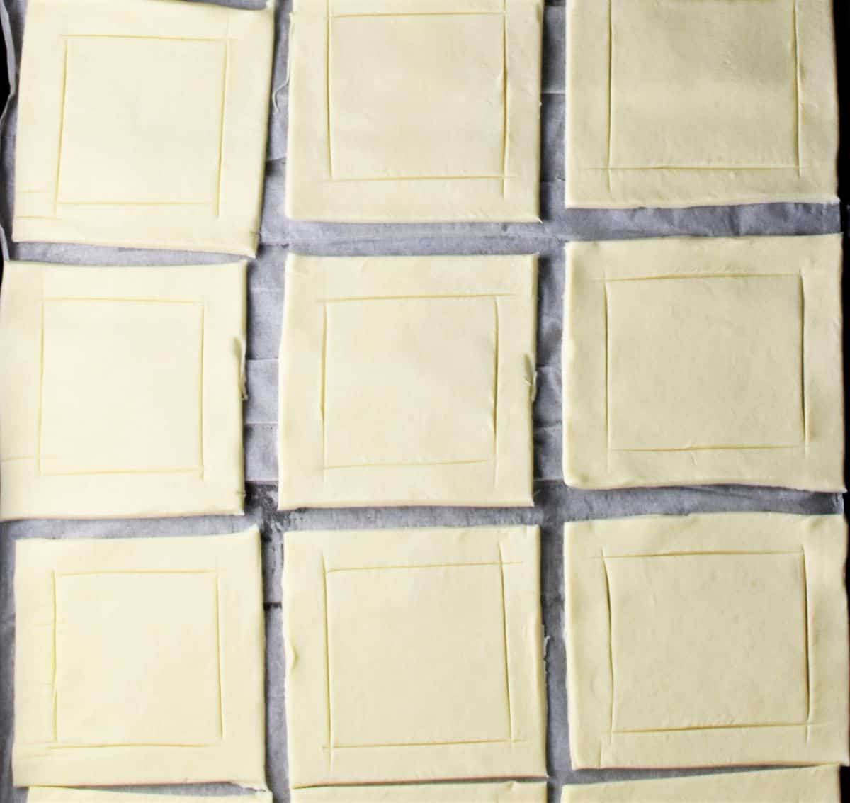 9 squares of puff pastry on top of parchement.