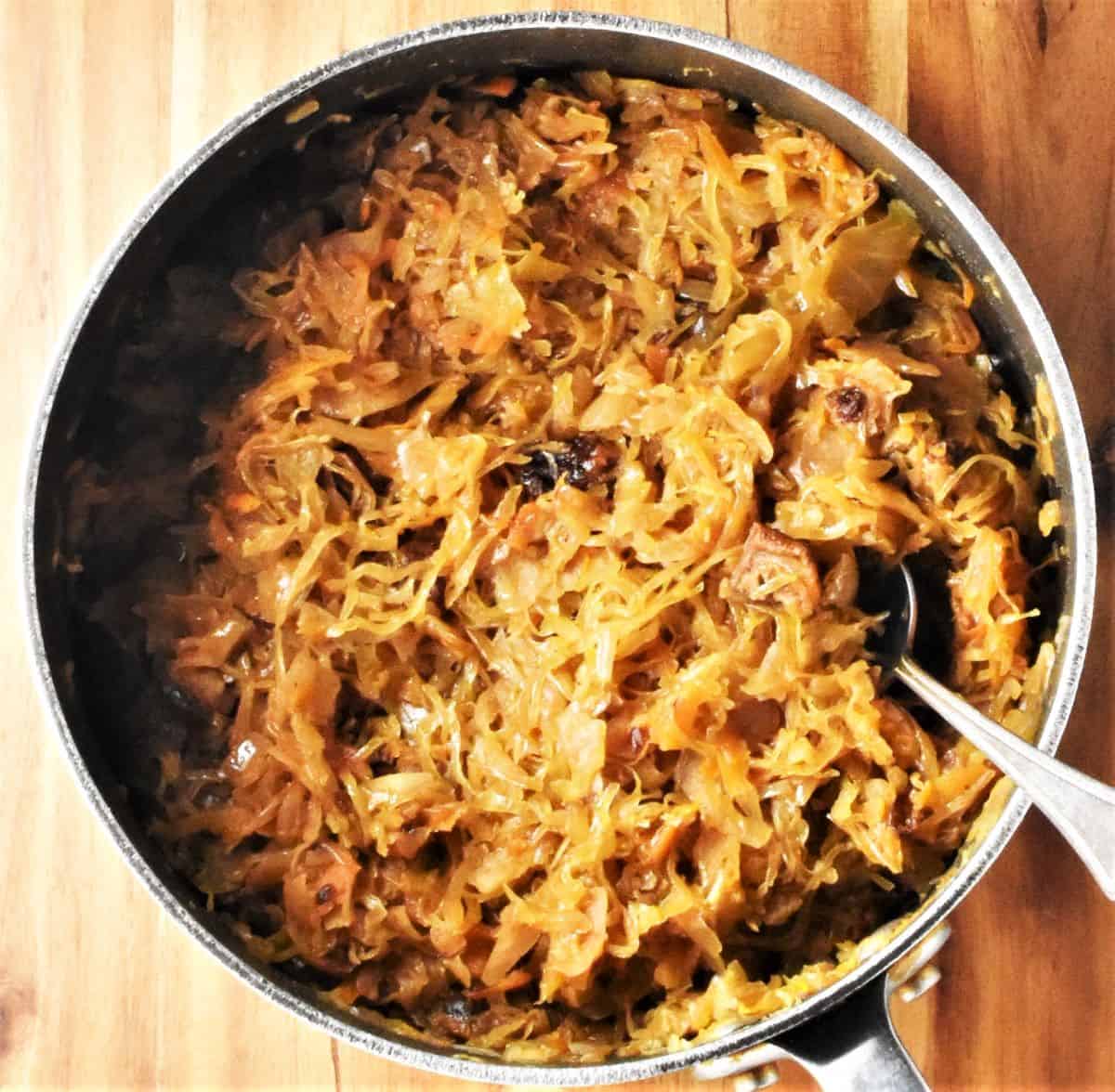 Top down view of cooked sauerkraut in pot with spoon.