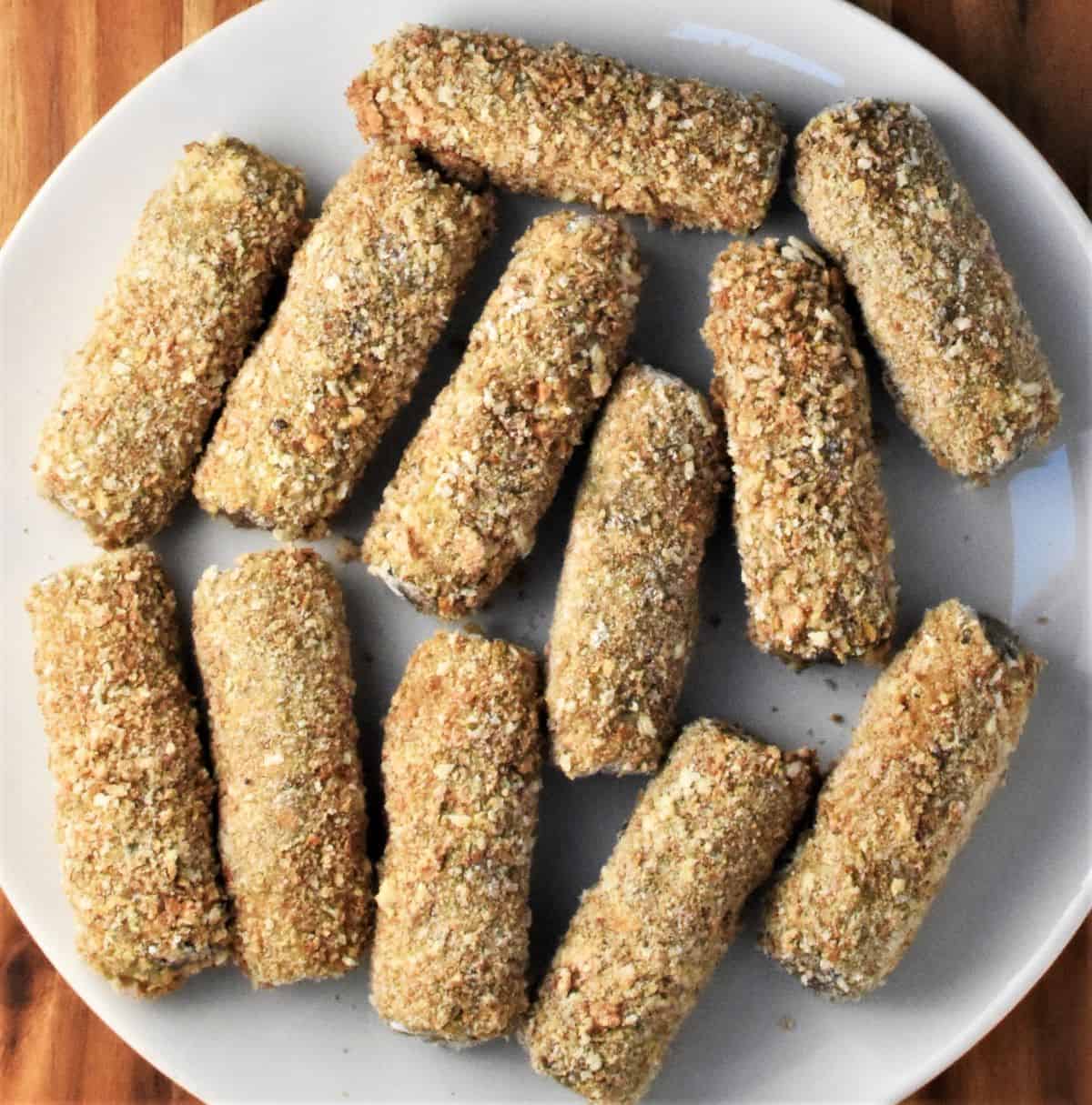 Breaded croquette rolls on white plate.