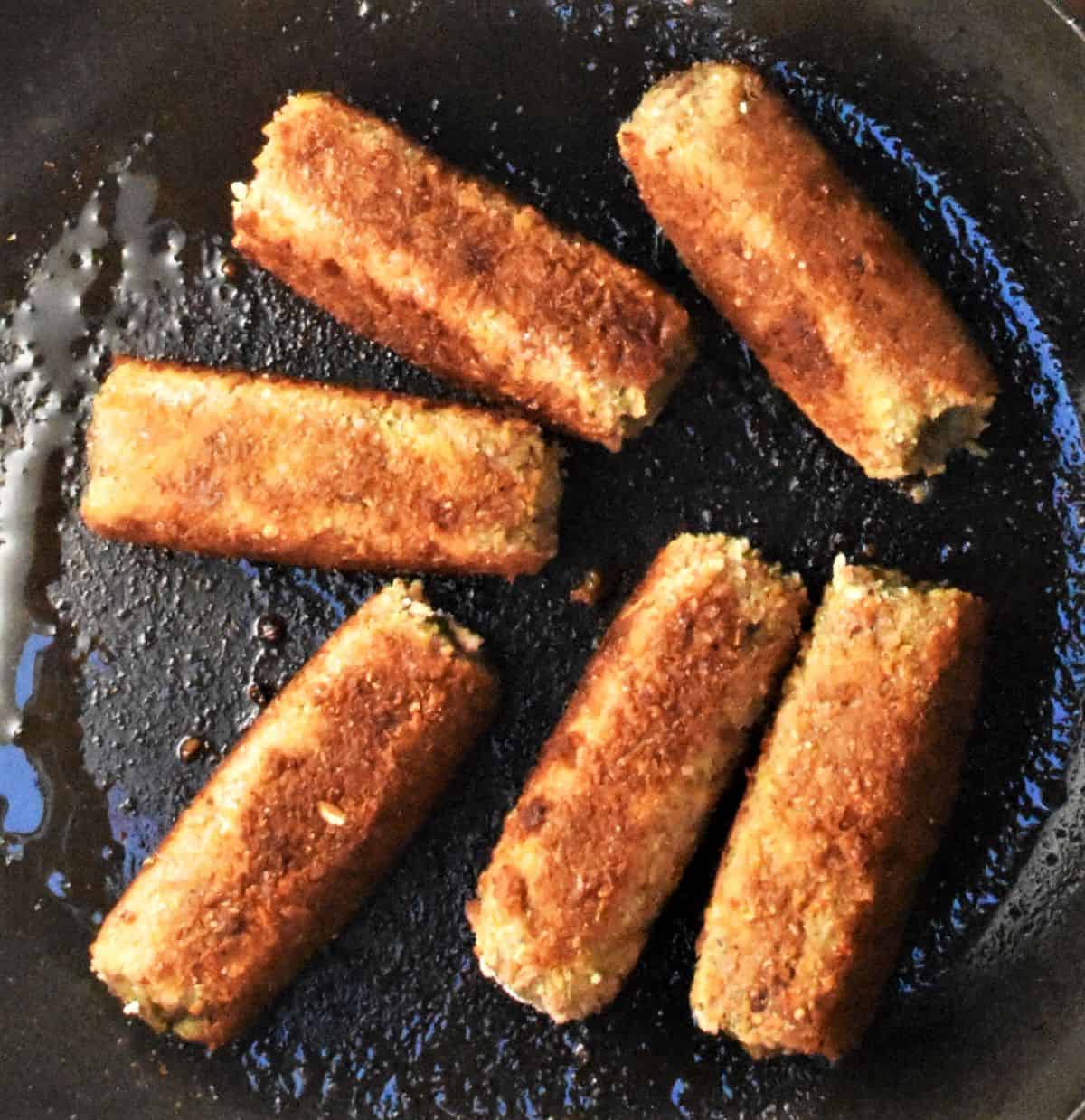 6 breaded croquettes in frying pan.
