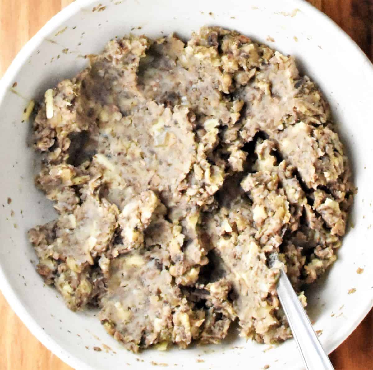 Mushroom filling for croquettes in white bowl with spoon.