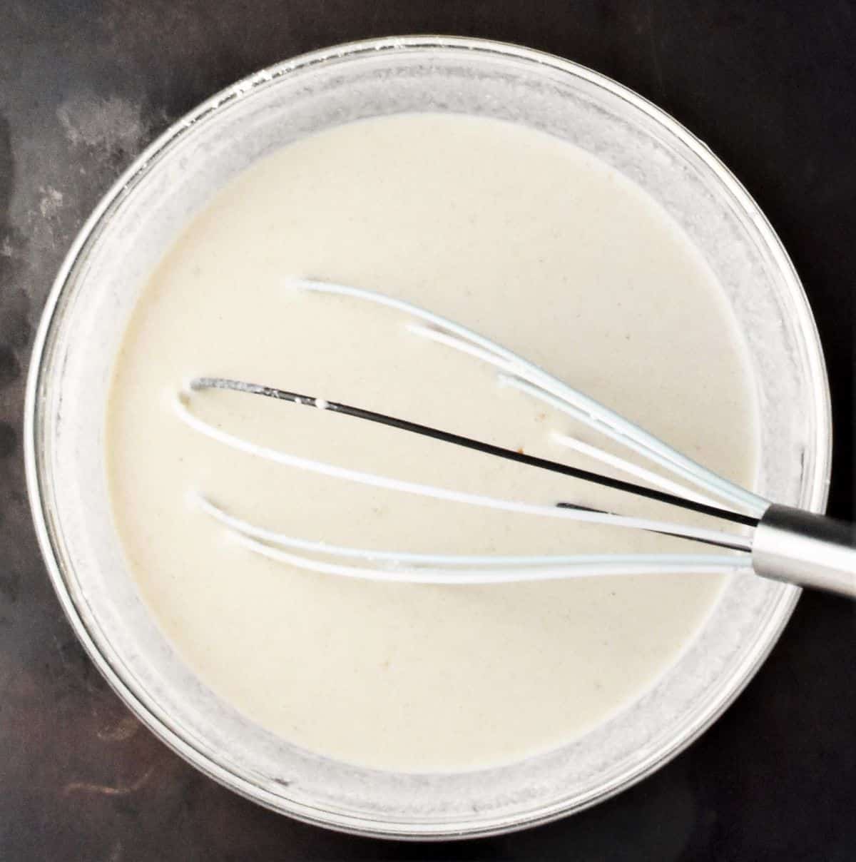 Smooth buckwheat crepe batter in mixing bowl with whisk.