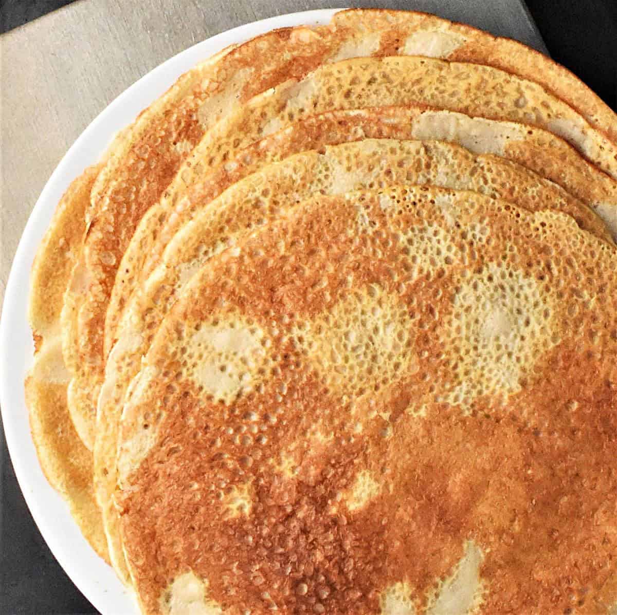 Top down view of crepes with buckwheat flour stacked on plate.