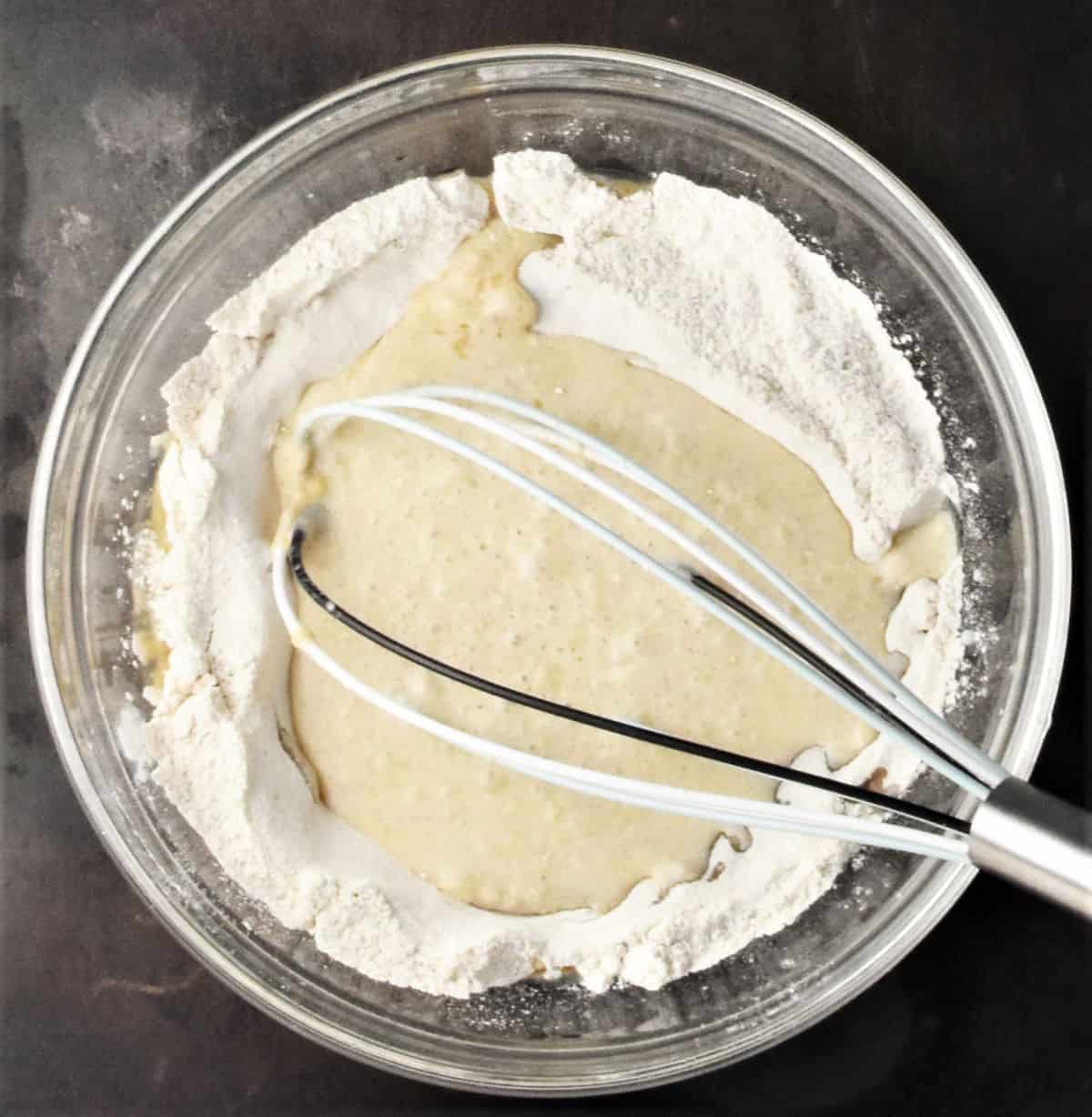 Making buckwheat crepe batter in bowl with whisk.