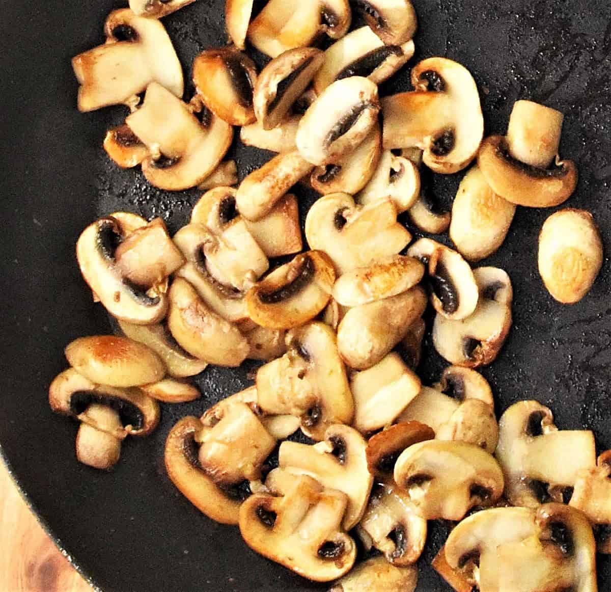 Top down view of sliced mushrooms in large pan.