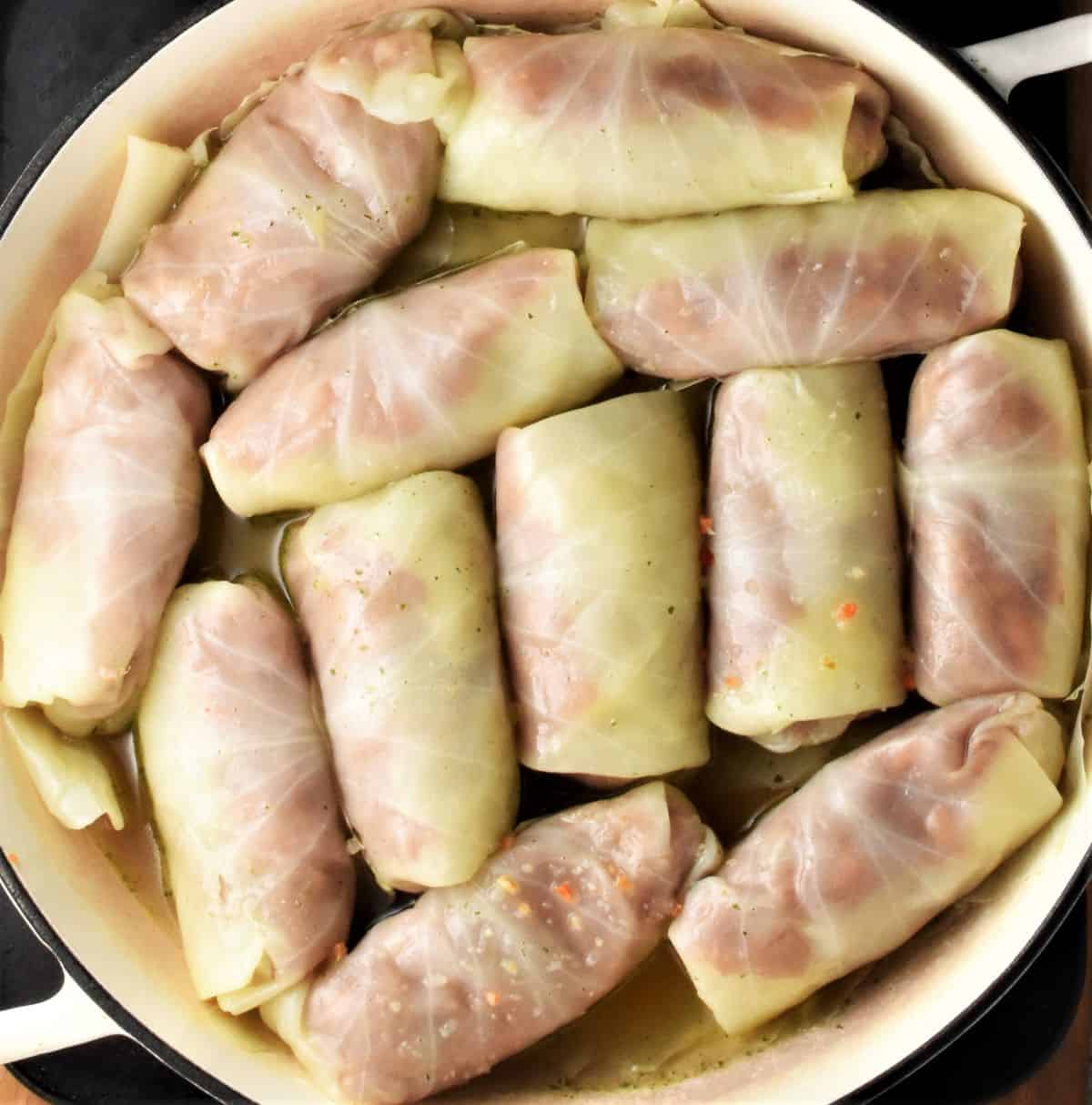 Top down view of cabbage rolls with stock in shallow dish.