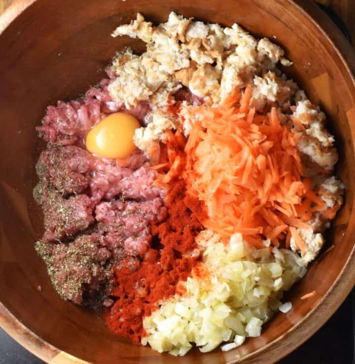 Top down view of ingredients for turkey stuffed cabbage rolls in brown wooden bowl.
